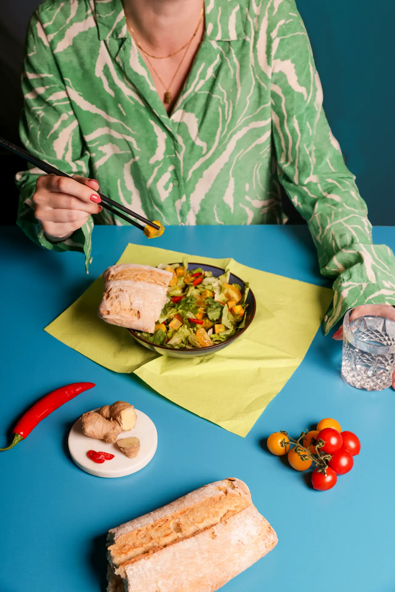 Tafel vol kaas met brood, cocktail glas en groente en fruit. Vrouw aan het lunchen